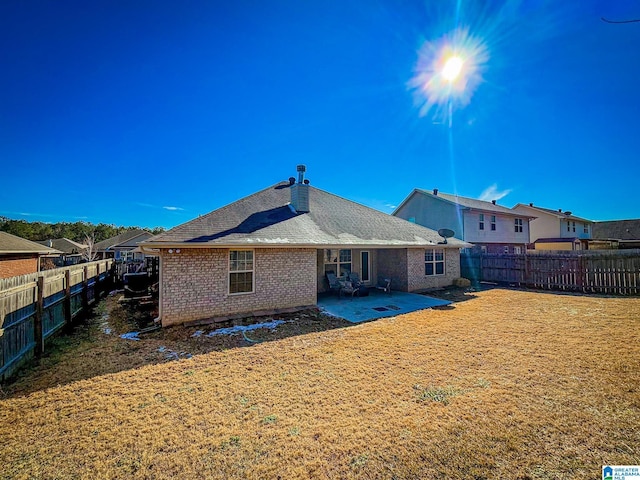 back of property with a yard and a patio