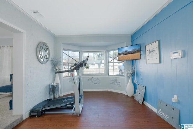 workout area with dark hardwood / wood-style flooring and crown molding