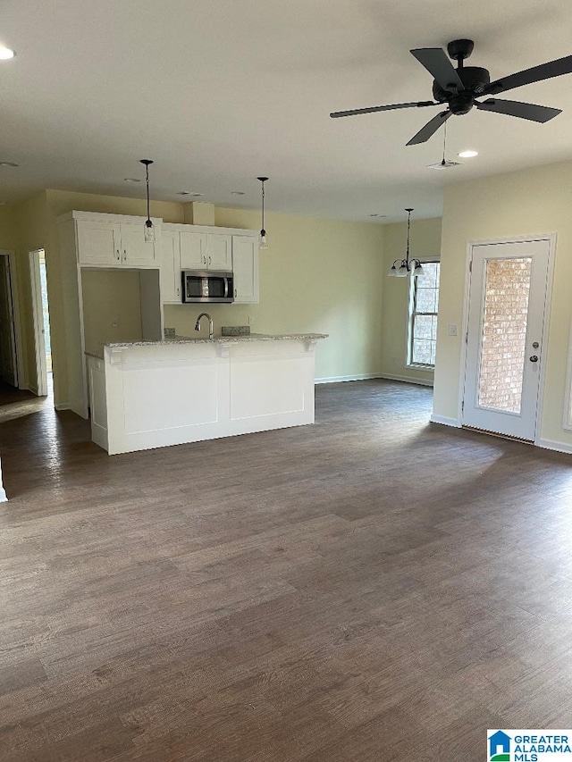 kitchen with light stone counters, dark hardwood / wood-style flooring, white cabinets, and decorative light fixtures