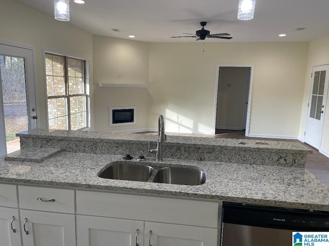 kitchen featuring dishwasher, sink, white cabinets, and light stone countertops