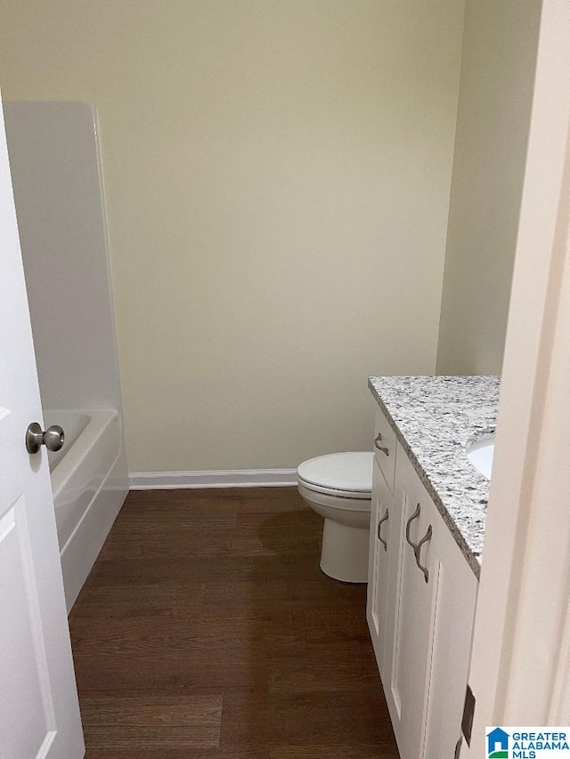 bathroom featuring vanity, a bathtub, toilet, and wood-type flooring