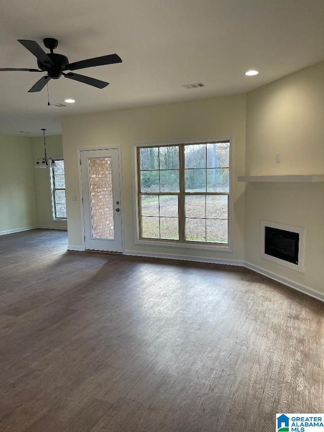 unfurnished living room featuring wood-type flooring and ceiling fan with notable chandelier