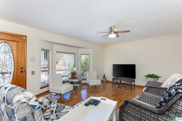 living area featuring wood finished floors, a ceiling fan, and baseboards