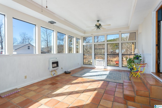 unfurnished sunroom featuring a tray ceiling, a healthy amount of sunlight, ceiling fan, and heating unit