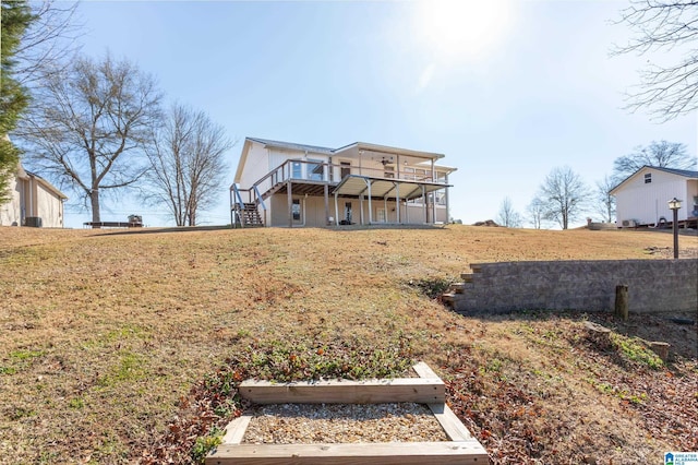 rear view of house with a lawn, a balcony, and a deck