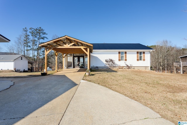 view of front of home featuring driveway, a front lawn, and metal roof