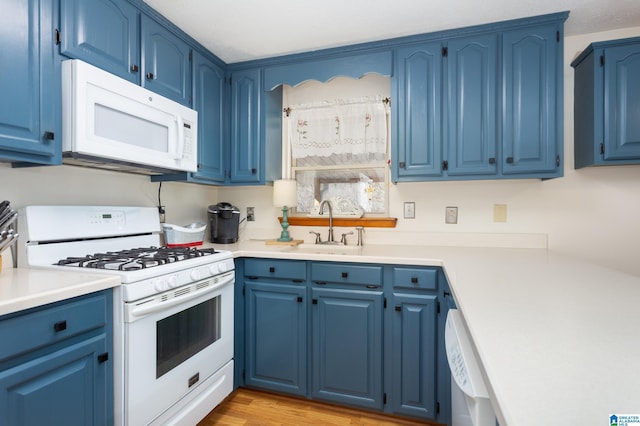 kitchen featuring white appliances, a sink, and blue cabinetry