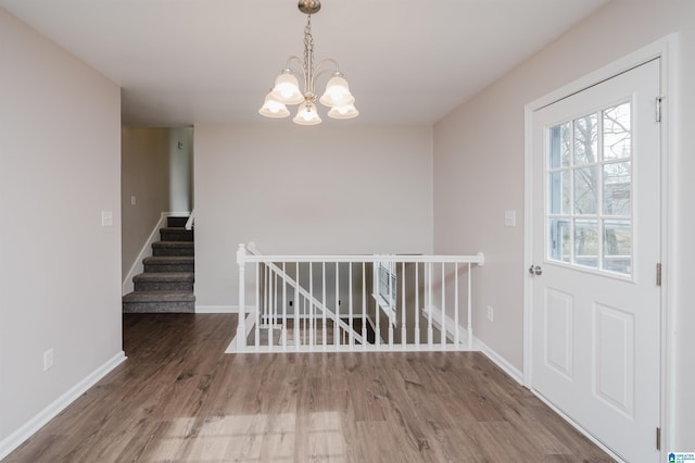 unfurnished dining area featuring a chandelier and hardwood / wood-style flooring