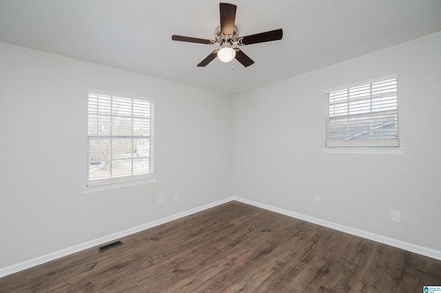 spare room with dark hardwood / wood-style flooring, ceiling fan, and plenty of natural light