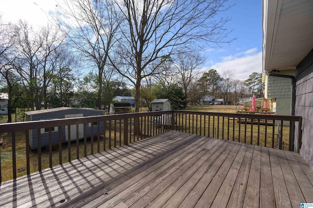 wooden terrace featuring a lawn and a storage shed