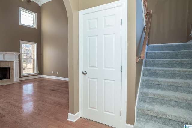 stairway with wood-type flooring and a tiled fireplace