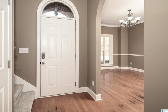 entrance foyer featuring hardwood / wood-style flooring, ornamental molding, and a notable chandelier