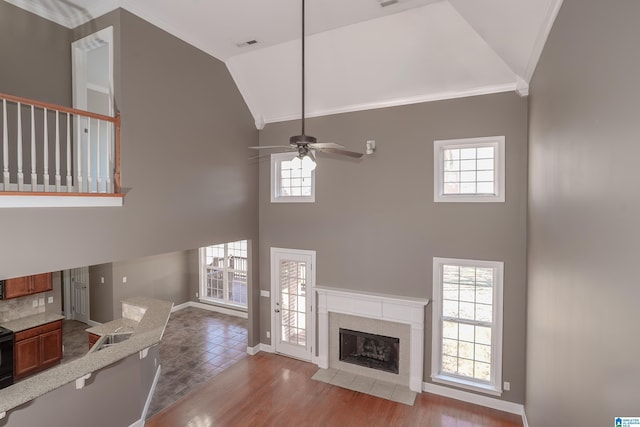 unfurnished living room with a fireplace, light hardwood / wood-style flooring, a wealth of natural light, and ceiling fan