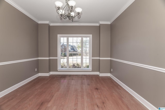 empty room featuring wood-type flooring, ornamental molding, and an inviting chandelier