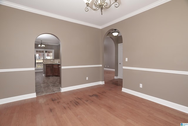 empty room featuring crown molding, dark hardwood / wood-style flooring, and an inviting chandelier