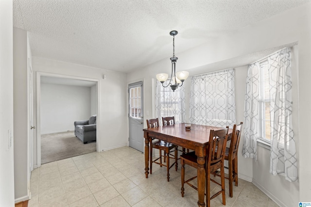 carpeted dining area featuring a chandelier and a textured ceiling