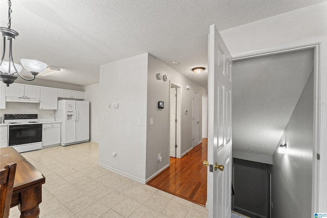 kitchen with hanging light fixtures, white cabinets, light tile patterned flooring, and white appliances