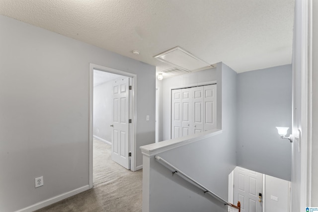 corridor with carpet floors and a textured ceiling