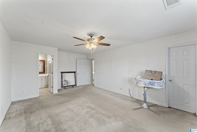 interior space featuring light carpet, ceiling fan, and a textured ceiling