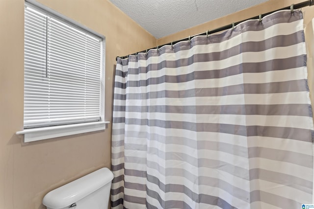 bathroom with a shower with shower curtain, a textured ceiling, and toilet