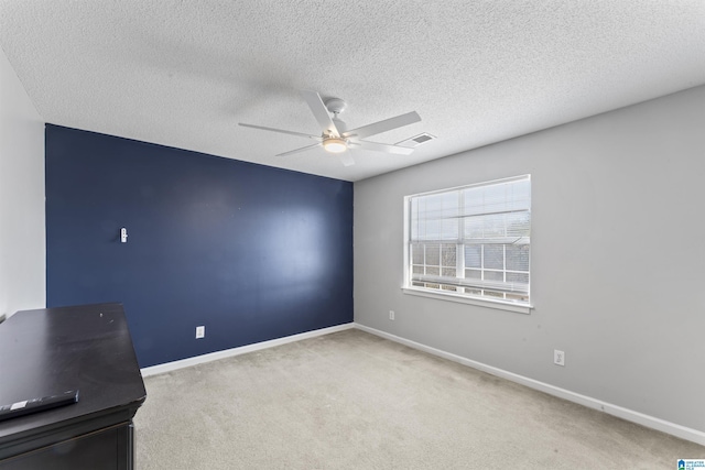 carpeted empty room featuring ceiling fan and a textured ceiling