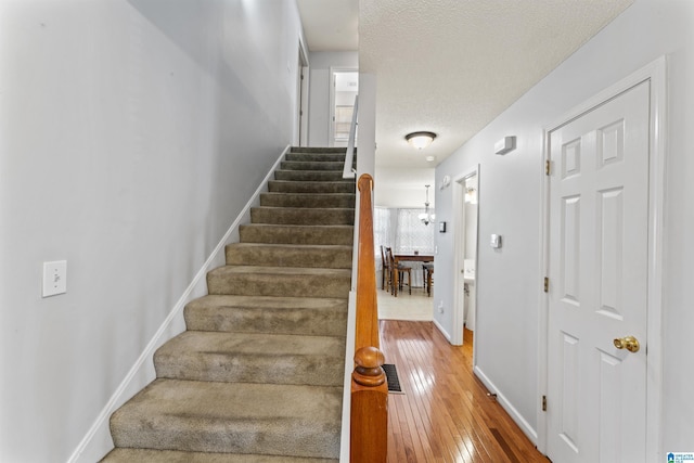 staircase featuring hardwood / wood-style floors and a textured ceiling