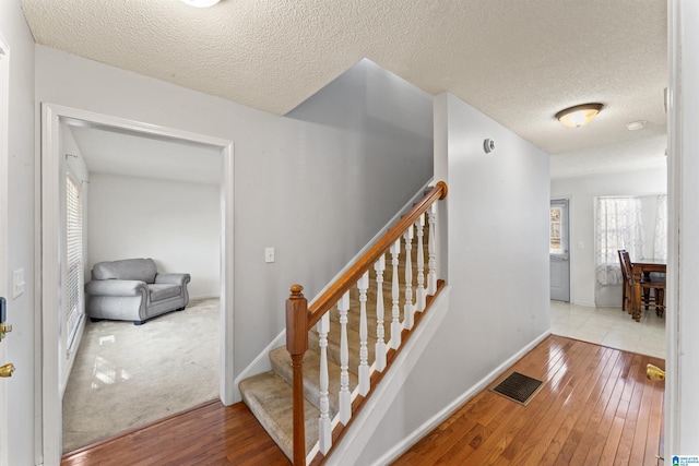 stairs featuring hardwood / wood-style flooring, plenty of natural light, and a textured ceiling