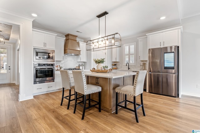 kitchen with a center island, premium range hood, tasteful backsplash, white cabinetry, and stainless steel appliances