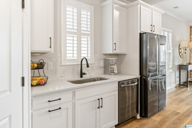 kitchen with stainless steel appliances, sink, light hardwood / wood-style flooring, white cabinetry, and plenty of natural light