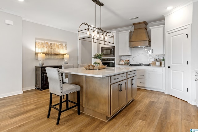 kitchen with premium range hood, white cabinets, decorative backsplash, appliances with stainless steel finishes, and a kitchen island