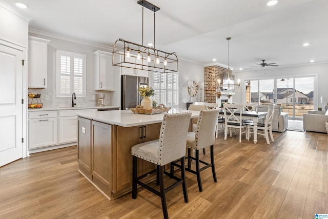 kitchen featuring white cabinetry, a kitchen island, hanging light fixtures, and stainless steel refrigerator