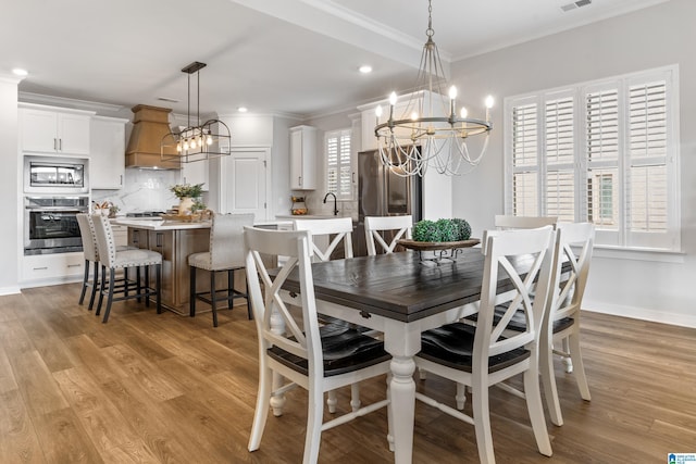 dining space featuring crown molding, a chandelier, and light wood-type flooring