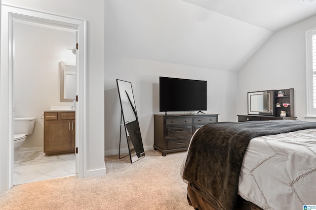 carpeted bedroom with ensuite bathroom and lofted ceiling