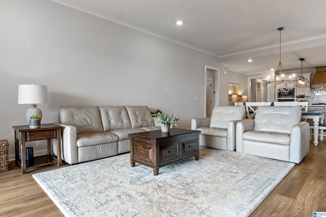 living room with light hardwood / wood-style flooring, ornamental molding, and a notable chandelier