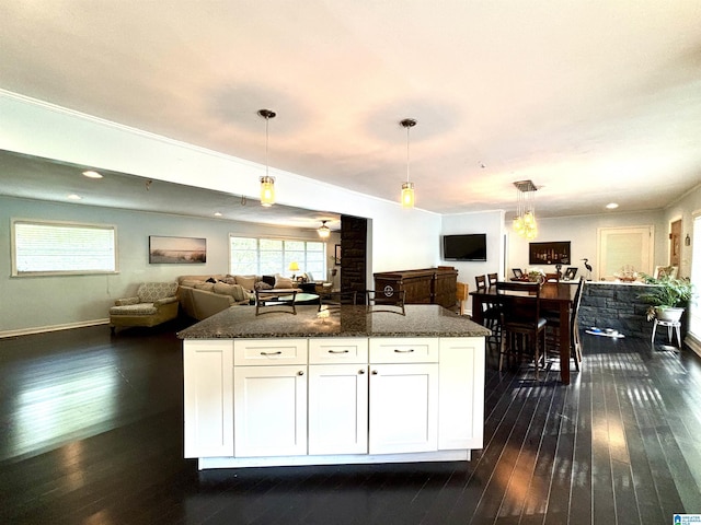 kitchen with white cabinets, decorative light fixtures, dark hardwood / wood-style flooring, and dark stone counters