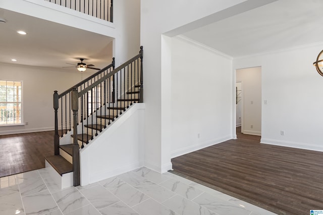 stairs featuring ceiling fan and crown molding