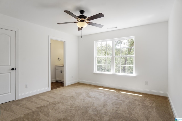 unfurnished bedroom with connected bathroom, ceiling fan, and light colored carpet