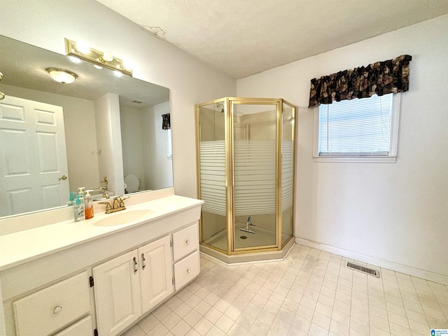 bathroom featuring vanity, toilet, a shower with door, and a textured ceiling