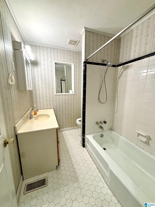 full bathroom featuring vanity, tiled shower / bath combo, toilet, ornamental molding, and a textured ceiling