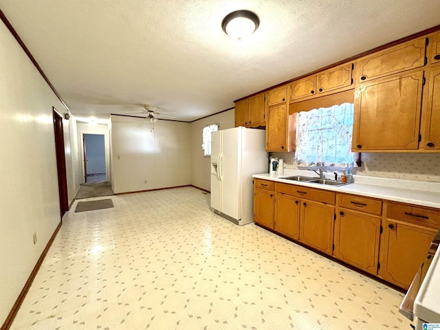 kitchen with a textured ceiling, ceiling fan, sink, and white refrigerator with ice dispenser