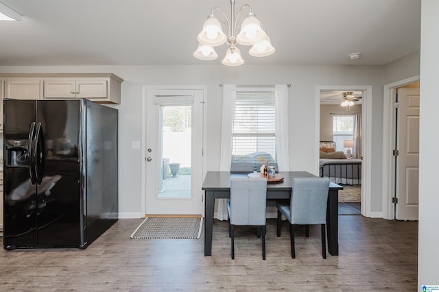 dining space featuring ceiling fan with notable chandelier and light wood-type flooring