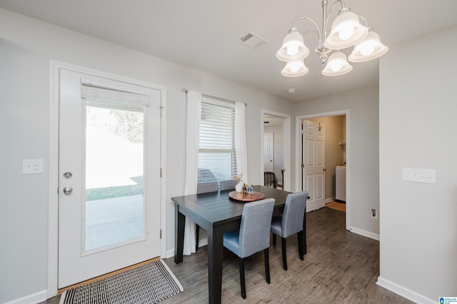 dining space with dark hardwood / wood-style floors and an inviting chandelier