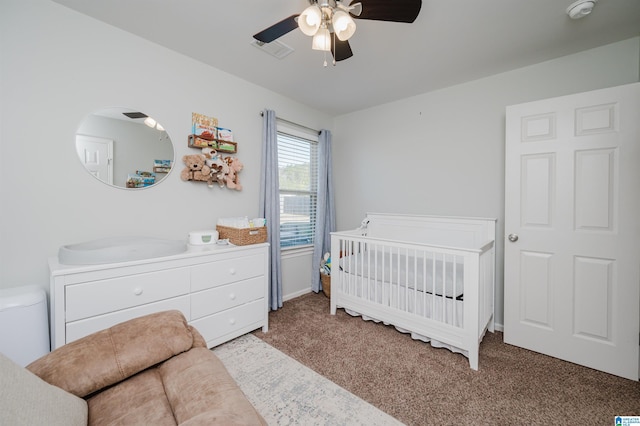 bedroom with a crib, carpet, and ceiling fan