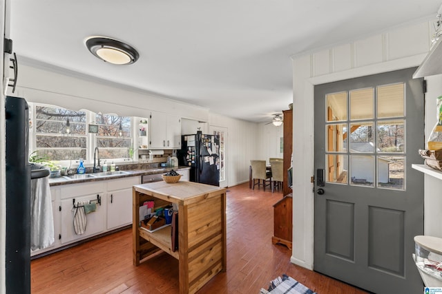 kitchen with a wealth of natural light, black refrigerator, white cabinets, and sink