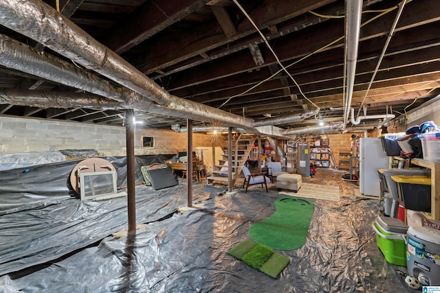 basement featuring electric water heater and white refrigerator