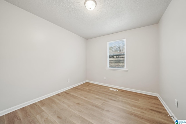 unfurnished room with a textured ceiling and light wood-type flooring