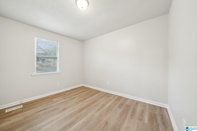 unfurnished room featuring light wood-type flooring and a textured ceiling