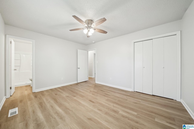 unfurnished bedroom with ensuite bath, ceiling fan, a textured ceiling, light hardwood / wood-style floors, and a closet