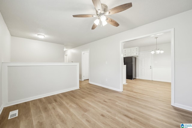 spare room with light wood-type flooring, a textured ceiling, and ceiling fan with notable chandelier