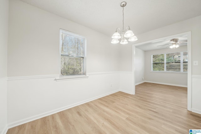 empty room with ceiling fan with notable chandelier and light wood-type flooring